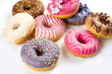 Dokuz farklı donut beyaz arka planda çekici bir şekilde düzenlenir. Her donut eşsiz renklere ve malzemelere sahiptir, tatlı tatlılar için mükemmel çeşitliliğe sahiptir..