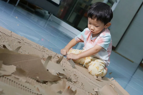 Bir çocuk, materyallerle çevrili kağıt etkinliklerine dikkatle odaklanır.