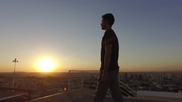 男摄影师在日落时在大楼顶上拍照 — 图库视频影像