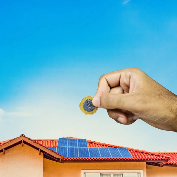 Ηλιακή πάνελ στην οροφή του σπιτιού και το χέρι κρατώντας βραζιλιάνικο — Φωτογραφία Αρχείου