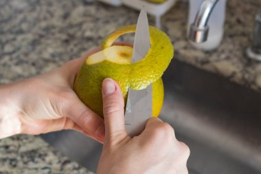 Meyve konsepti - Mutfakta turuncu kesen kadın elleri