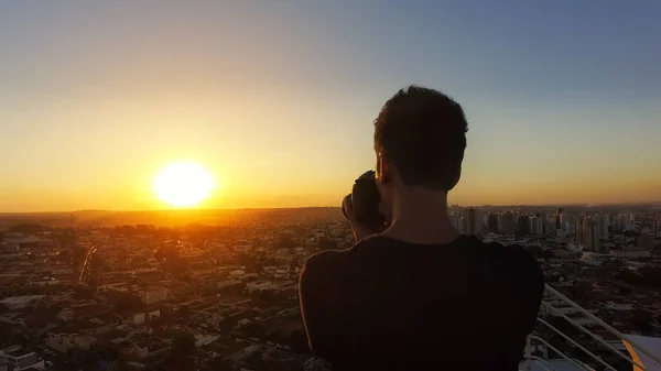 Silhouette of a photographer taking pictures on top of the building at sunset