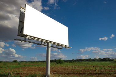 Reklam panosu, kırsal bir yerde güzel bulutlu gökyüzünün önündeki boş ilan panosu. Metin veya tasarım için boşluk