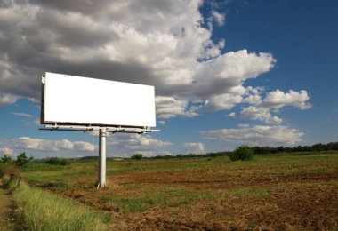 Reklam panosu, kırsal bir yerde güzel bulutlu gökyüzünün önündeki boş ilan panosu. Metin veya tasarım için boşluk