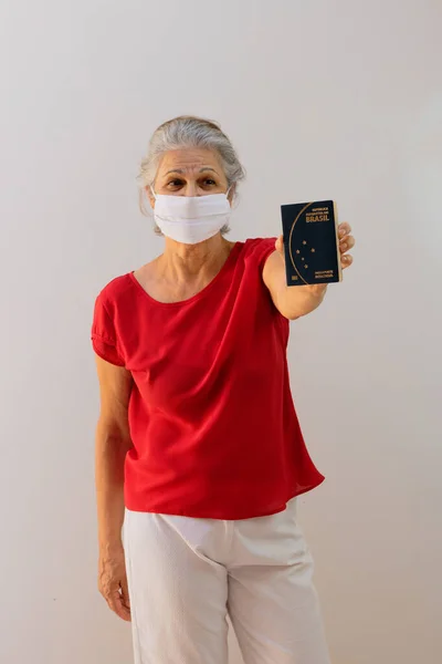 ブラジルのパスポートを持っているパンデミックマスクを持つ女性 メルコスール 隔離された白い背景 — ストック写真