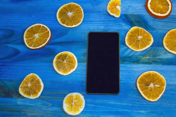Smartphone Mavi Ahşap Zemin Üzerine Portakal Dilimleri Ile Dekore Edilmiştir — Stok fotoğraf