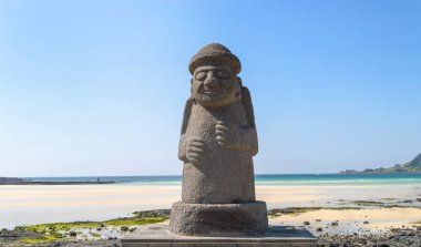 Dol hareubang - Jeju Adası deniz güneşli gün ve arka plan kumsalda sembolü heykeli Jeju Adası, Güney Kore, 10 Eylül 2015: