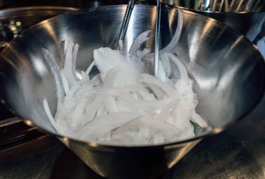 Metalik kabın içinde kesilmiş beyaz soğan görünümü kadar çubuk parçası ile kapatmak