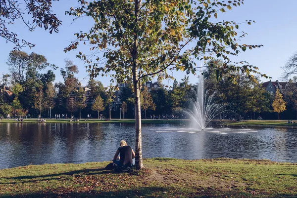 Mladá žena čte knihu u jezera ve Vondelparku — Stock fotografie