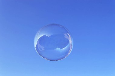 Gün ışığında mavi gökyüzünde yüzen büyük yuvarlak sabun köpüğü.