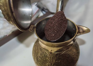 Kahve yapmak için bronza kaşık ile öğütülmüş kahve ekliyorum.