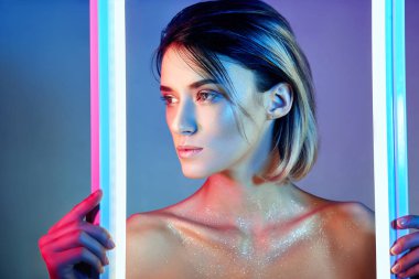 Neon ışık iç çamaşırı seksi kadın. Neon ışıkları ve parlamayı kızın yüzündeki ışığın. Pullu parlak kontrast ışık arka plan üzerinde çıplak kadın. Yüzünde güzel makyaj ile sarışın
