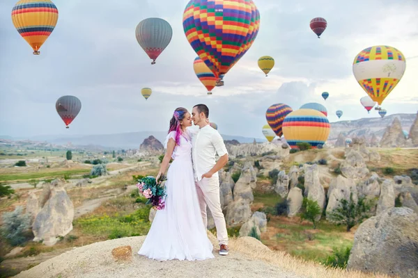 愛のカップルは カッパドキアのバルーンの背景に立っています 男と女の丘の上は 空飛ぶ風船の数が多いを見てください トルコ カッパドキア山の童話風景 自然に結婚式 — ストック写真