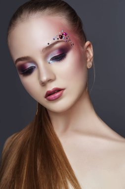 Sanat makyajı kadınlar kaşlar üzerinde birçok rhinestones farklı şekiller, güzel pürüzsüz cilt bakımı yüz. Güzellik makyaj kadın yüz yakın çekim yaparken. Profesyonel makyaj sanatçısı, uzun güzel saç