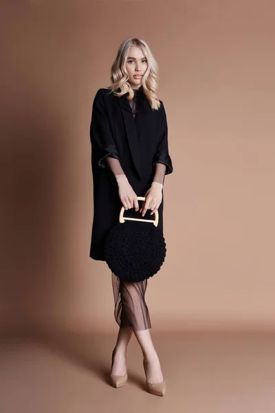 Mulher Loira Bonita Posando Casaco Preto Com Saco Fundo Bege — Fotografia de Stock