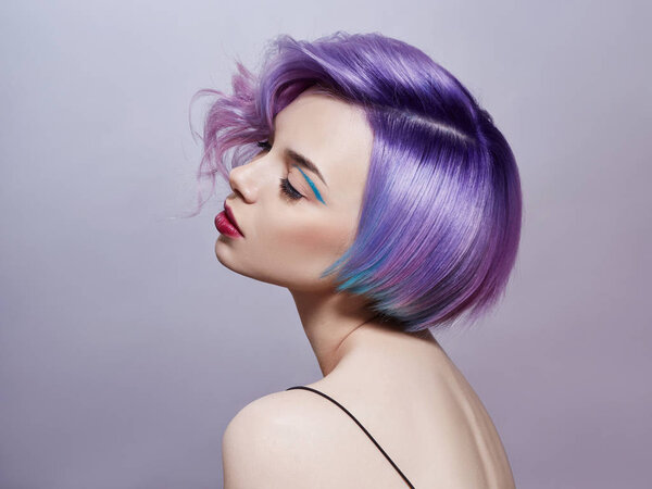 Portrait of a woman with bright colored flying hair, all shades of purple. Hair coloring, beautiful lips and makeup. Hair fluttering in the wind. Sexy girl with short  hair. Professional coloring
