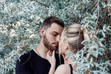 Hugs ve seven çalılar dallarında çift öpücük. Yol boyunca, bir adam bir kadınla öpüşürken yürümek. Aşk, sevgi, ilişki, yüzünde canlı duygular. Doğu sevgi dolu çift