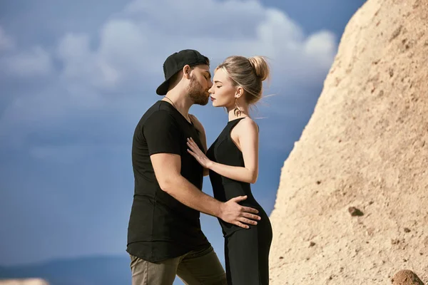 In love Eastern couple in mountains of Cappadocia hugs and kisses. Love and emotions loving couple vacationing in Turkey. Closeup portrait man and woman. Beautiful Crescent moon earrings on girl ears