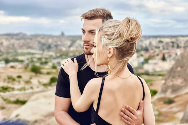Kapadokya'nın dağlarında Doğu çift aşık hugs ve öper. Aşk ve sevgi dolu duygular Türkiye'de tatil çift. Portre portre erkek ve kadın. Güzel Crescent moon küpe kız kulakları üzerinde