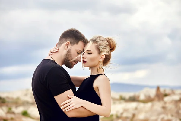 Love and emotions loving couple resting in Turkey. In love Eastern couple in the mountains of Cappadocia hugs and kisses. Close-up portrait of a man and woman. Beautiful Crescent earrings on girl ears