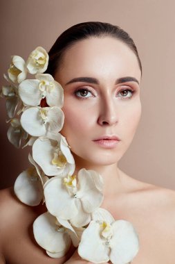 Güzel parlak makyaj pembe ruj kız yüz yakınındaki beyaz orkide olan kadın. Nazik sanat portre reklam kozmetik, profesyonel makyaj sanat, parlak dudaklar, parlak renkli, gözleri mavi gölgeler