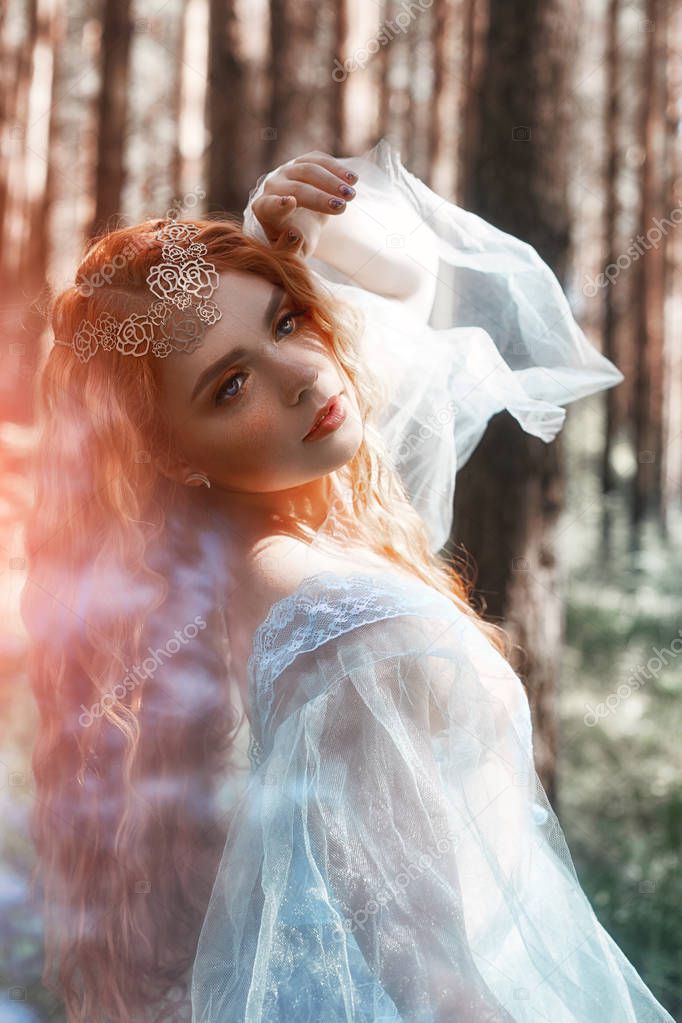 Beautiful redhead woman forest nymph in a blue transparent light dress in the woods spinning in dance. Red hair girls. Art fashion portrait of fairy woman fairy tale in summer forest