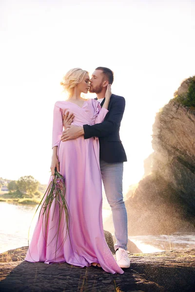 Güzel genç çift hugs ve uzak ve birbirimize romantik bir tarih Nehri üzerinde zevk görünüyor. Erkek ve kadın gün batımında güneş deniz kenarında buzlu ayakta