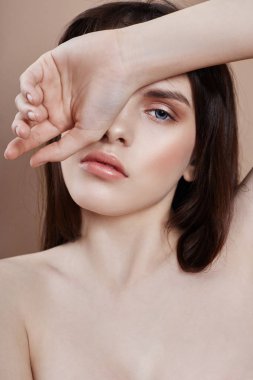 Sexy brunette in leather jacket and red top, portrait bright makeup and lipstick close-up, face makeup, professional makeup, skin care. Young sexy woman posing on beige background, flying hair