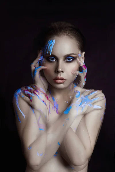 Portrait woman in drops of color paint on black background. Art Paint on the girl face and hands, fashion beauty and makeup. Double exposure overlay, no focus. Mysterious portrait splashes blue paint