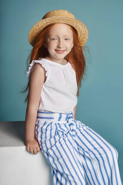 挪威女孩与明亮的红色头发在草帽 美丽的红头发的女婴 长发和美丽的蓝色大眼睛 红头发的女孩在夏天衣服摆在蓝色背景 — 图库照片