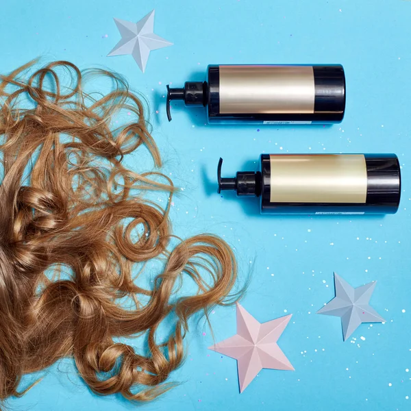 头发护理 长美丽的头发和洗发水 化妆品护理强健康的根 头发躺在蓝色的背景上 美发师配件 完美的发型 顶视图 书桌美发师化妆品 — 图库照片