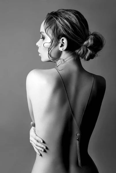 裸体时尚的艺术裸体在灰色背景的后面的金发 挂件项链链在后面 美容和皮肤护理完美的身体 女孩拥抱她的手 — 图库照片