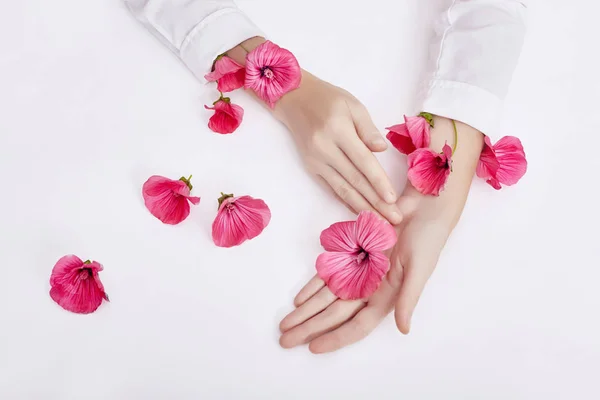 La mano y la flor de color primavera están en el cuidado de la piel de la mesa. Cosme naturaleza — Foto de Stock