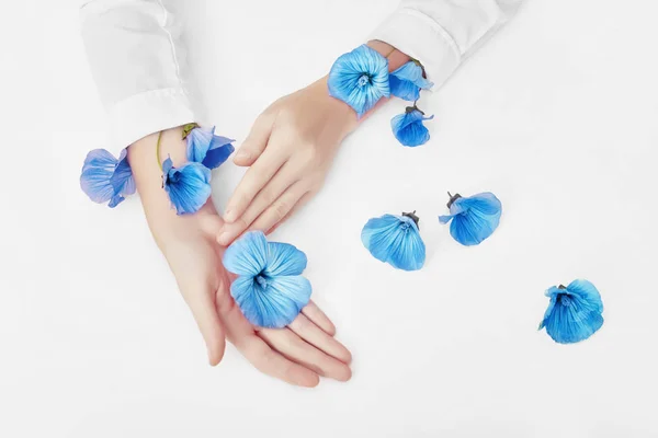 La mano y la flor azul primavera están en el cuidado de la piel de la mesa. Naturaleza Cosmet — Foto de Stock