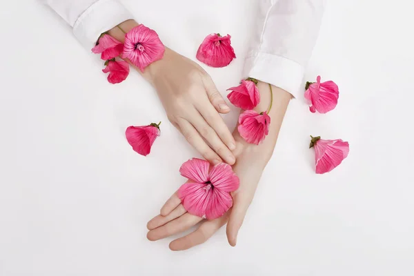 La mano y la flor de color primavera están en el cuidado de la piel de la mesa. Cosme naturaleza — Foto de Stock