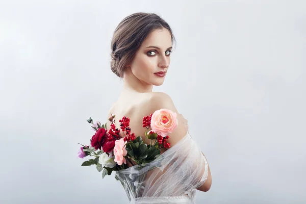 Woman with a bouquet of artificial flowers behind her. The girl — Stock Photo, Image