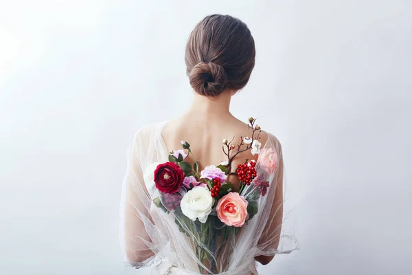 Mulher com um buquê de flores artificiais atrás dela. A menina — Fotografia de Stock