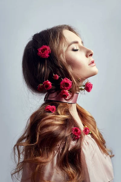Mulher bonita com flores de rosa em seu cabelo longo, um curativo — Fotografia de Stock