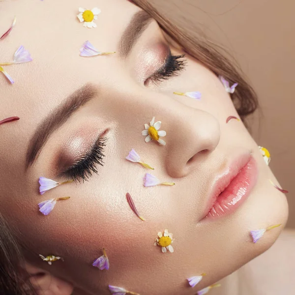 Pétalas de flores no rosto menina, cosméticos mulher para hidratar rosto s — Fotografia de Stock