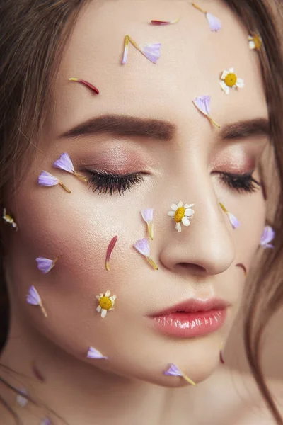 Pétalas de flores no rosto menina, cosméticos mulher para hidratar rosto s — Fotografia de Stock