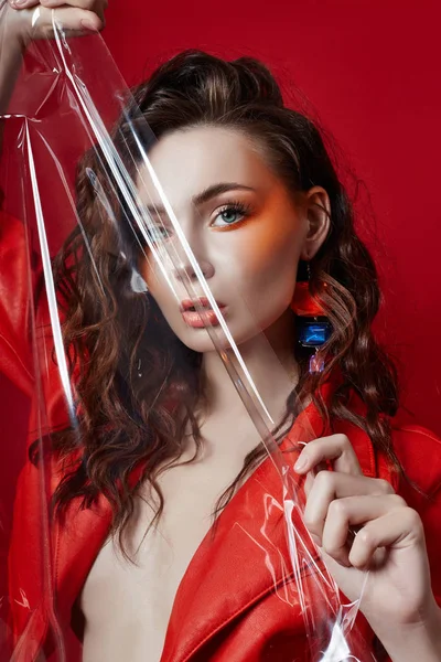 Bellissimo trucco della donna nuda sexy in giacca rossa sul retro rosso — Foto Stock