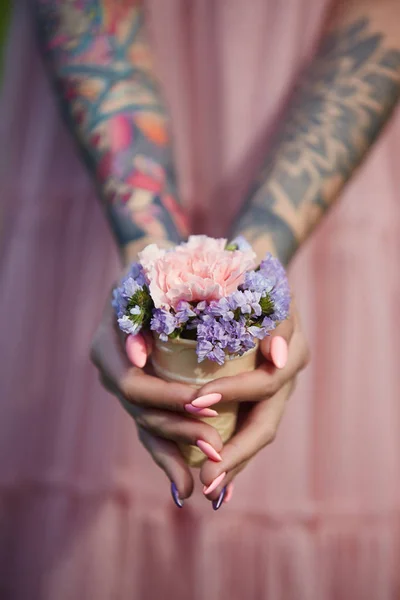 Lindas flores nas mãos de uma menina com tatuagens, cosméticos — Fotografia de Stock