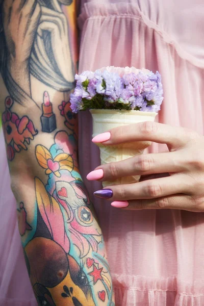 Mooie bloemen in de handen van een meisje met tatoeages, cosmetica — Stockfoto