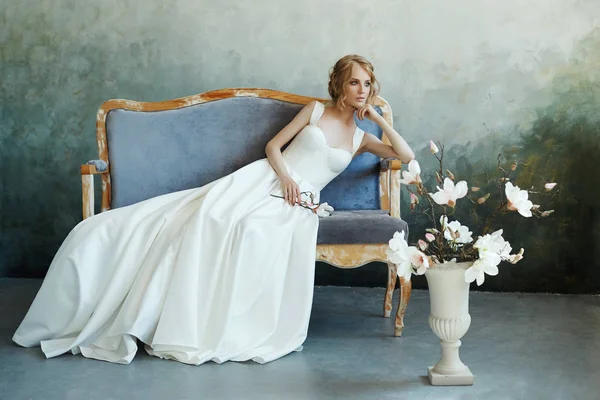 Noiva em um vestido longo chique deitado no sofá sofá. Casamento branco — Fotografia de Stock