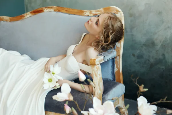 Novia en un vestido largo elegante acostado en el sofá sofá. Boda blanca — Foto de Stock