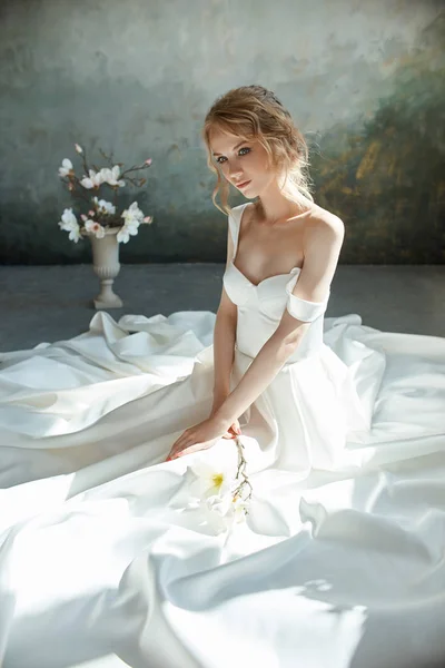 Chica en un vestido largo elegante sentado en el suelo. Boda blanca dr — Foto de Stock