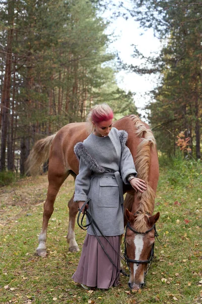 Woman walking with horse autumn on nature. Creative hot pink mak