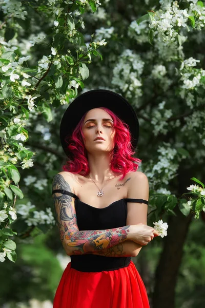 Дівчина моди з яскраво-червоним пофарбованим волоссям в яблуко і бузкову квітку — стокове фото
