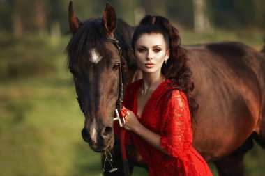 Uzun elbiseli kız bir atın yanında duruyor, güzel bir kadın.