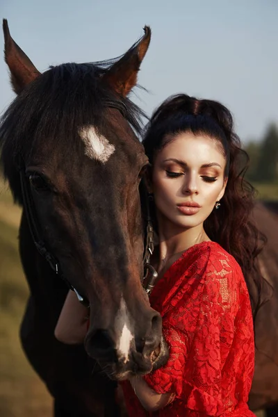 Meisje in een lange jurk staat naast een paard, een mooie vrouw stro — Stockfoto